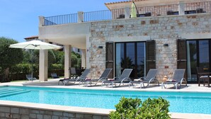 A poolside area with lounge chairs and a covered seating area.
