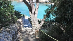 A stone staircase leading to a coastal area with a clear view of the sea.