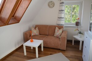 Una sala de estar acogedora con un sofá marrón, una mesa de centro blanca y una ventana con cortinas.
