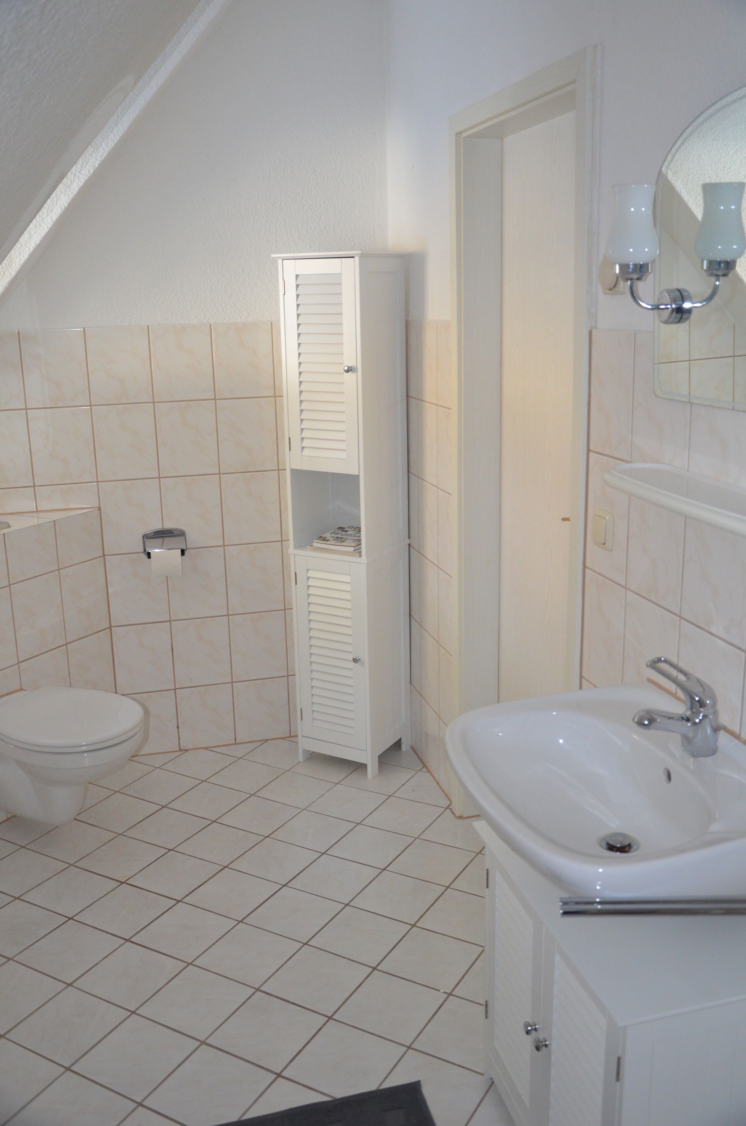 Une salle de bain comprenant des toilettes, un lavabo, un porte-serviettes et un meuble pour ranger les serviettes.