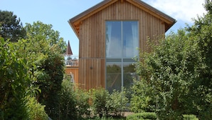 A wooden cabin with a large window and a balcony, surrounded by dense greenery. - Lakeside new direct lakeside location lakeside terrace, bathing lake, biosphere wifi (salem)