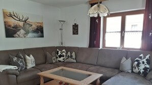 A modern living room with a sectional sofa, a glass-top coffee table, and decorative pillows.