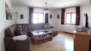 A living room with a brown sofa, a wooden coffee table, and a television on a wooden stand.