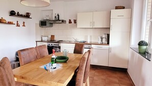 A compact kitchen with a dining table, chairs, and basic appliances.