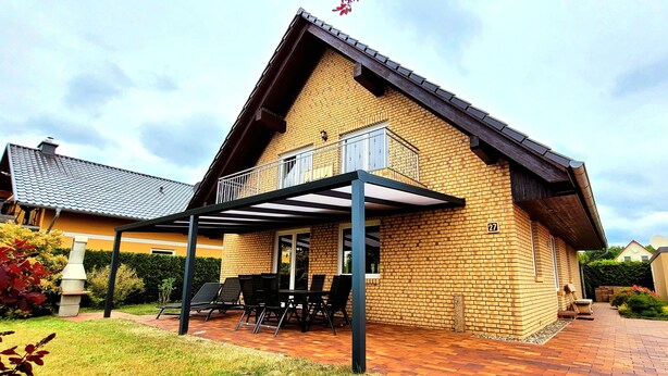 A two-story house with a balcony, a patio with outdoor furniture, and a brick exterior.
