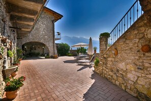 A stone courtyard with a brick pathway, outdoor seating, and a view of the mountains. - Rustico Kristi by Theater Home, with marvellous lake view (Tignale)
