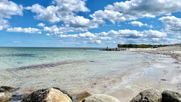 A beach with clear water, rocks, and a distant shoreline. - Hühnerstall -Shower, terrace, beach chair, sauna, near the beach, child-friendly (Pugholz)