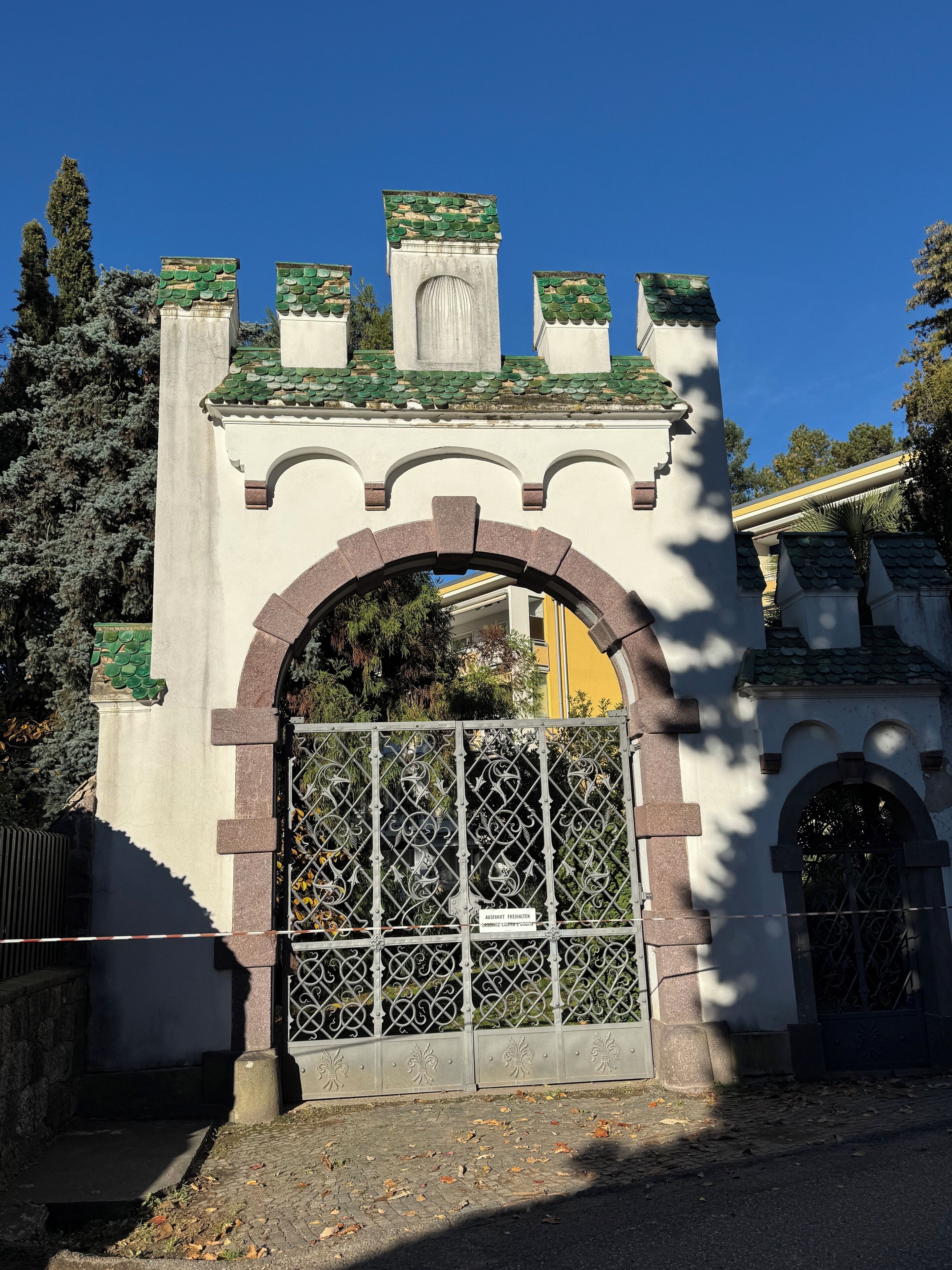 Uma entrada fechada por portão, com um arco decorativo.