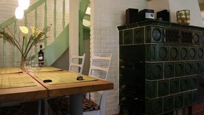 Un'area pranzo con un tavolo in legno, sedie bianche e un mobiletto verde decorato con motivi circolari.