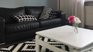 A modern living room with a black leather sofa, a white coffee table, and a patterned rug. - NEW! Modern 3-room apartment in Lüneburg, close to the city, quiet, outskirts (Lüneburg)