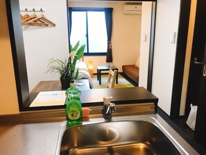 A modern kitchen with a stainless steel sink, a bottle of dish soap, and a potted plant. - GH One More Heart at Kamishichiken 3 (Kyoto)