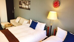Une chambre d’hôtel avec deux lits, un canapé, une petite table, une lampe et une horloge murale.