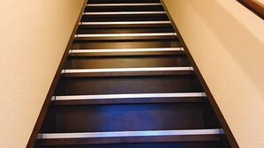 Un escalier avec des marches en bois et une rampe métallique, qui monte.