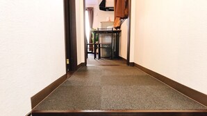Un couloir étroit doté d’un plancher en bois foncé et d’un mur blanc.