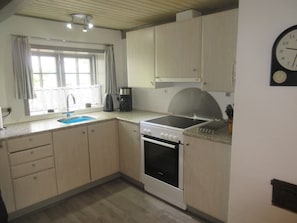 Cocina compacta con lavabo, estufa y un reloj en la pared.
