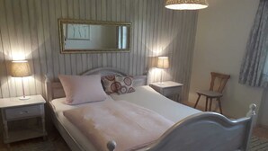 A neatly arranged bedroom with a bed, two bedside tables, a chair, and a mirror on the wall. - Heissbauer - Cozy "Obstgarten" Vacation Rental with Mountain Views - Ideal for Families (Wackersberg)