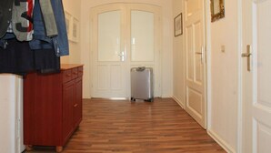 A hallway with wooden flooring, a red dresser, and a silver suitcase.