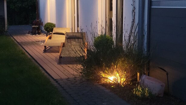 Une maison avec une allée pavée, un banc et un petit jardin agrémenté de plantes.