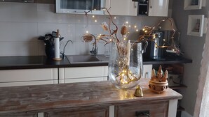 Une cuisine avec des meubles blancs, un plan de travail en bois et un vase décoratif illuminé.