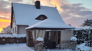 Une maison recouverte de neige, avec un patio abrité.