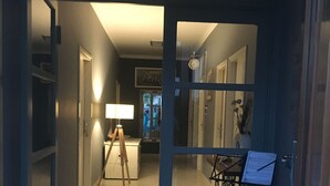 A narrow hallway with a staircase leading to a landing. There is a clock on the wall and a framed picture above the door. - MODERN APARTMAN - 4 TO 6 PERSONS WITH A STUNNING SEA VIEW (TISNO)