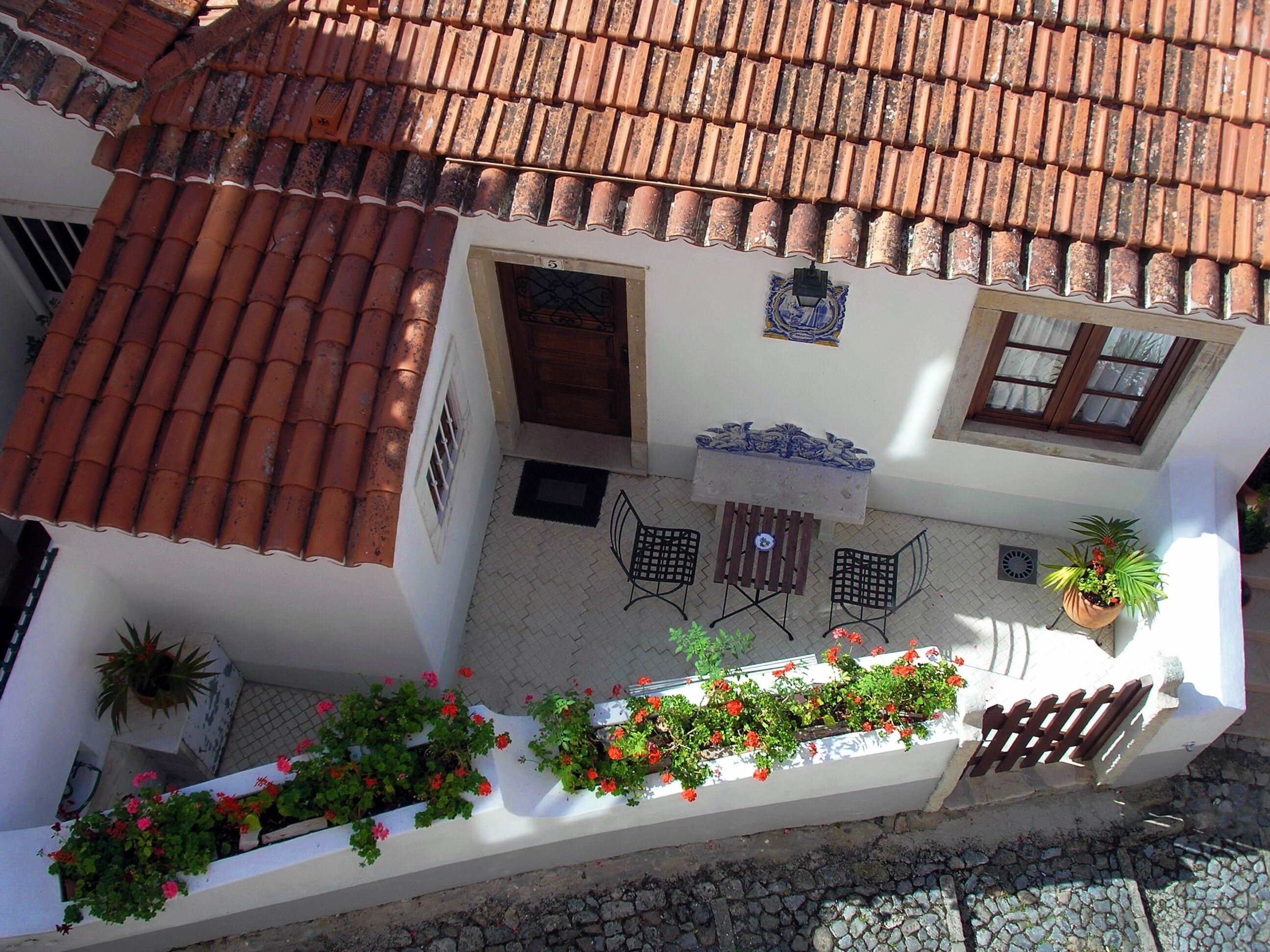 A courtyard with a tiled roof, a small table with chairs, and potted plants.