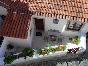 A courtyard with a tiled roof, a small table with chairs, and potted plants. - Very central and quiet apartment for two people (Sintra)