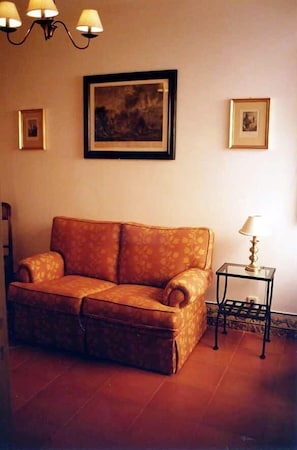 A living room with a sofa, a small table with a lamp, and framed pictures on the wall. - Very central and quiet apartment for two people (Sintra)
