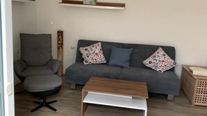 Een moderne woonkamer met een grijze bank, gestreepte kussens, een houten salontafel en een grijze fauteuil.