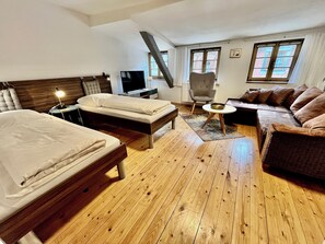 Une chambre dâhĂŽtel avec deux lits, un canapĂ©, un fauteuil, une tĂ©lĂ©vision et une fenĂȘtre.