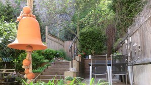 A garden with a wooden staircase, a hanging bell, and a metal candelabra. - live individually and modernly in old walls (Görlitz)