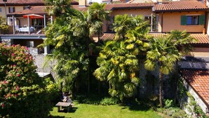 A residential area with houses, palm trees, and a stone wall. - Rustic modern apartment with atmosphere at Lago Maggiore (Verbania-Biganzolo)