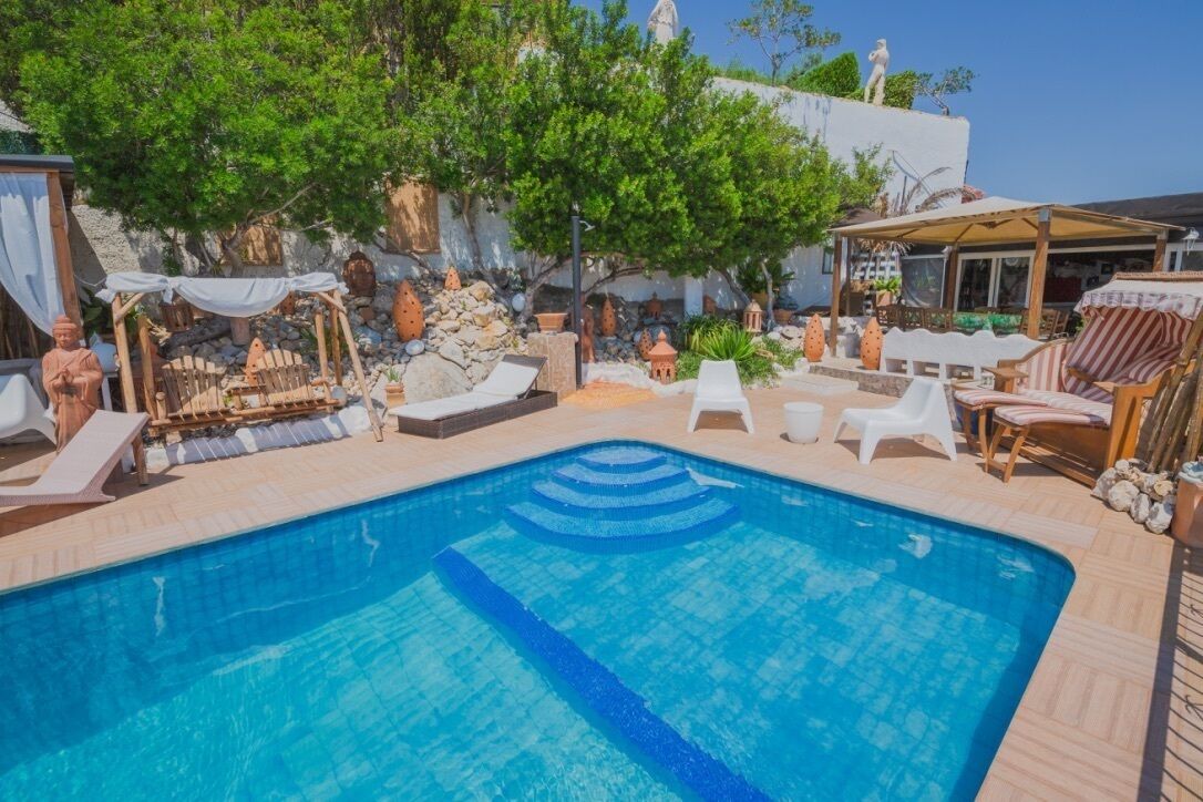A swimming pool with lounge chairs and a pergola.