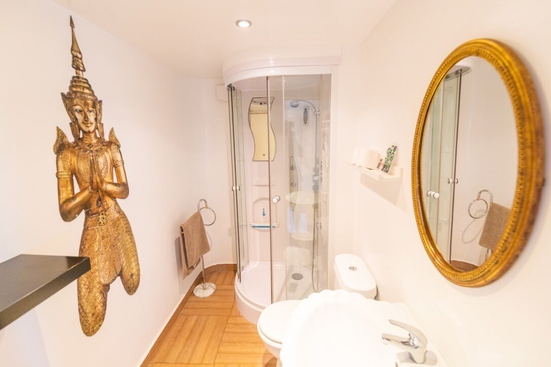 Bagno con toilette, lavandino, doccia e una statua dorata.