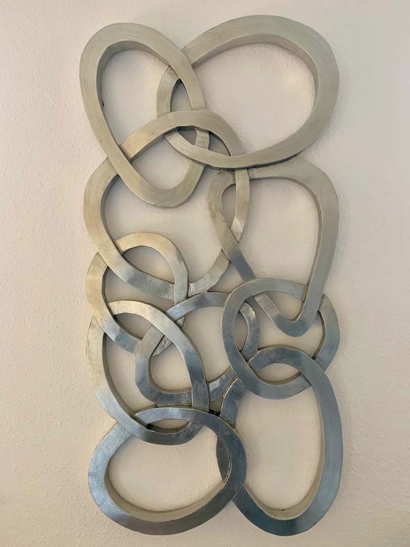 Eine Wand mit einer metallischen, abstrakten Skulptur.