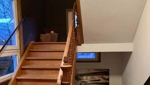A wooden staircase with a handrail, leading to a lofted area with skylights.