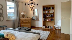 A bedroom with a bed, a dresser, a bookshelf, a chair, and a window.
