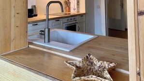 A modern kitchen with a wooden countertop, stainless steel sink, and a built-in oven.
