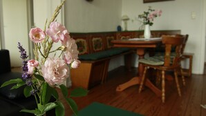Un coin repas avec une table et des chaises en bois, un banc et un vase de fleurs.