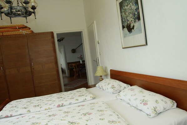 Un dormitorio con dos camas, un armario de madera y un cuadro en la pared.