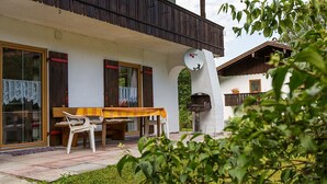A rustic wooden building with a covered patio area featuring a table and chairs. - Apartment with stunning mountain views - dream vacation in the mountains (Schönau am Königssee)