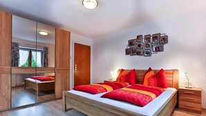 A modern bedroom with a large bed, wooden wardrobe, and a mirror. - Apartment with stunning mountain views - dream vacation in the mountains (Schönau am Königssee)