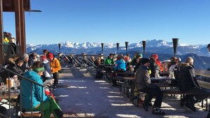 Eine Terrasse mit Tischen und Stühlen mit Blick auf ein Gebirge.