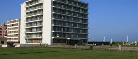A multi-story hotel with a modern design, featuring a series of balconies and large windows.