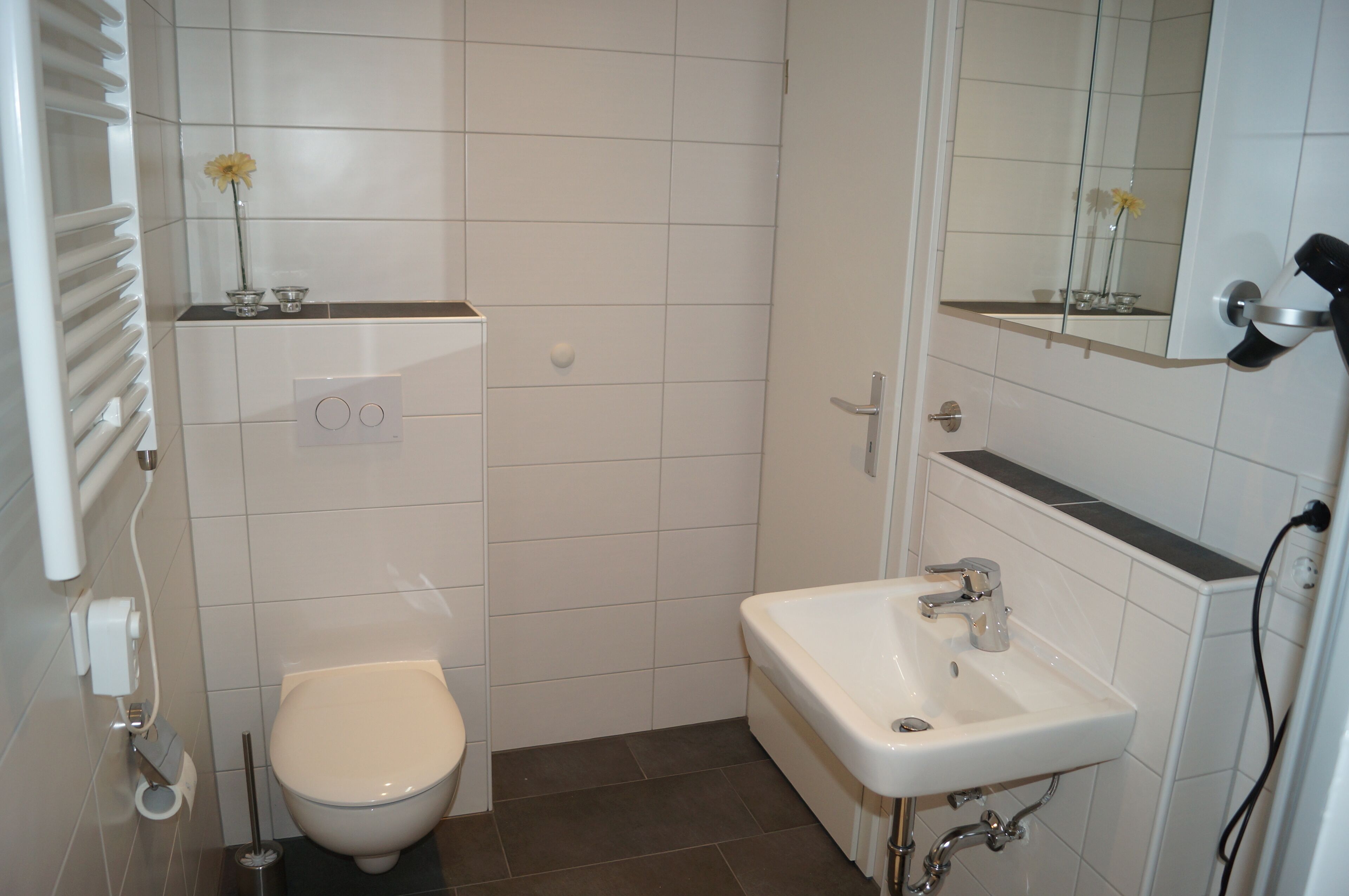 A small bathroom with a toilet, sink, and mirror.
