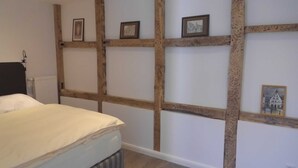 A bedroom with a bed, wooden beams, and framed pictures on the wall. - Apartment Anna for 6 persons - Apartments Rheine Markt 12 (Rheine)