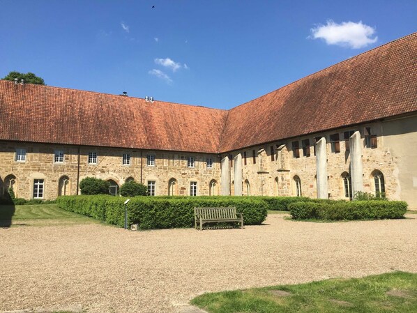 Une cour intérieure avec un bâtiment dont le toit est recouvert de tuiles rouges et les murs sont en pierre.