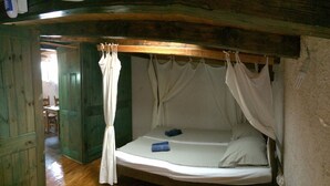 A rustic bedroom with a wooden ceiling, a single bed with white bedding, and a canopy. -  Freckle, bed & bike (Betina,Murter)