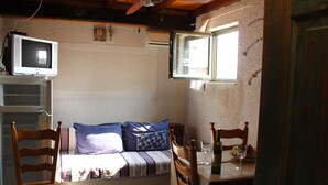 A small, cozy room with a bed, a television, a dining table with chairs, and a window. -  Freckle, bed & bike (Betina,Murter)