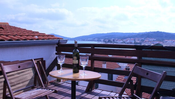 A terrace with a table and chairs, a bottle of wine, and two glasses. -  Freckle, bed & bike (Betina,Murter)